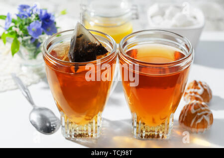 Deux tasses de thé chaud, des biscuits et du miel. Fleurs dans l'arrière-plan.Le processus d'infusion de thé. Focus sélectif. Banque D'Images