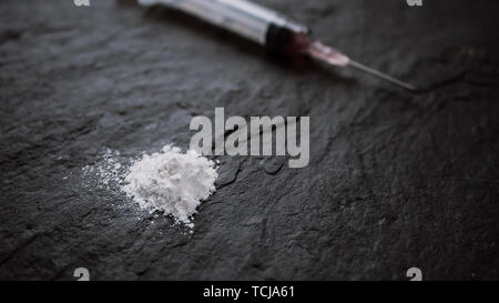 Toxicomane concept. close up de la seringue et l'héroïne cuit sur fond noir Banque D'Images