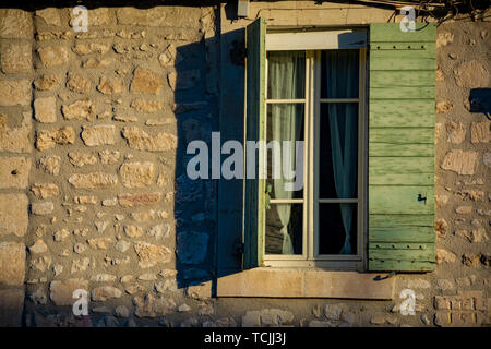 Vue sur fenêtre dans maison médiévale en Provence dans les feux du soleil au lever du soleil, au sud de la France Banque D'Images