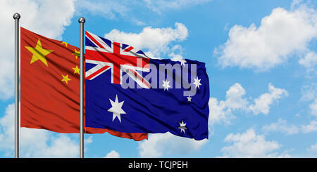 La Chine et l'Australie drapeaux dans le vent contre ciel bleu nuageux blanc ensemble. Concept de diplomatie, de relations internationales. Banque D'Images