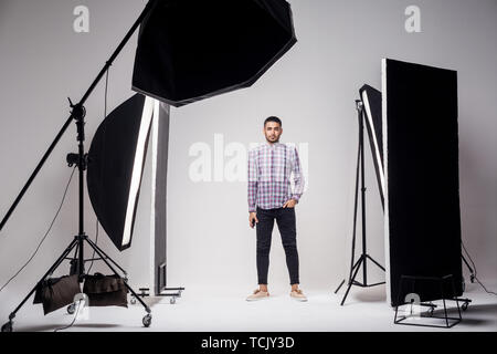 Studio de photographie professionnelle montrant les coulisses de la mode. feux beau jeune homme modèle au studio en le voyant clignote, debout et lookin Banque D'Images