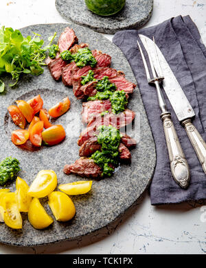 Tranches de steak de boeuf avec sauce au chimmichuri sur plaque de pierre grise Banque D'Images