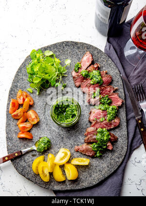 Tranches de steak de boeuf avec sauce au chimmichuri sur plaque de pierre grise Banque D'Images