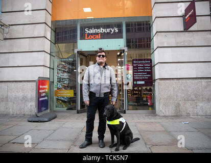 Ski alpin paralympique britannique John Dickinson-Lilley avec son chien-guide, Brett, l'extérieur du magasin Sainsbury's sur Southampton Row à Holborn, centre de Londres, à quelques minutes de la chaîne de supermarchés a son siège social, où il a été deux fois refusé l'entrée avec son chien. Banque D'Images