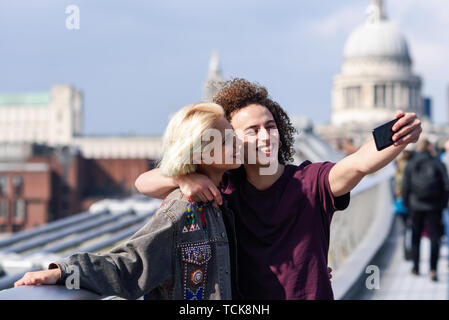 Couple heureux de prendre une photo sur selfies London's Millennium Bridge Banque D'Images