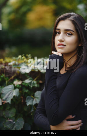 Fille brune marche à travers le parc en automne Banque D'Images