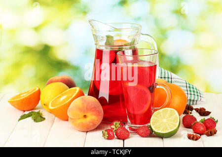 Pot en verre de sangria et de fruits, sur une table en bois, sur fond vert Banque D'Images