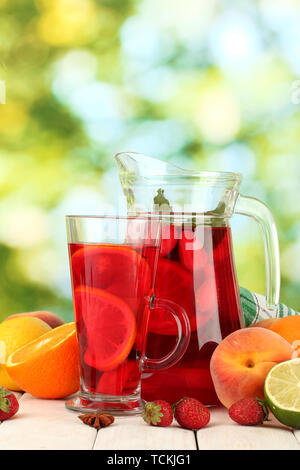 Pot en verre de sangria et de fruits, sur une table en bois, sur fond vert Banque D'Images