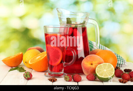 Pot en verre de sangria et de fruits, sur une table en bois, sur fond vert Banque D'Images