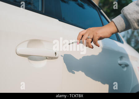 Femme avec des clés de voiture. Voiture d'ouverture de porte. Woman's hand déverrouiller une porte sur une voiture. La lumière du soleil. Le transport. Banque D'Images