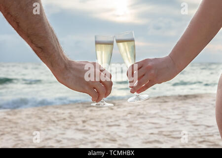 Close-up of a person tintement des verres de champagne dans les mains At Beach Banque D'Images