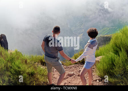 Couple debout sur le bord du ravin en arrière de l'appareil photo. Pico do Arieiro sur l'île portugaise de Madère. Banque D'Images