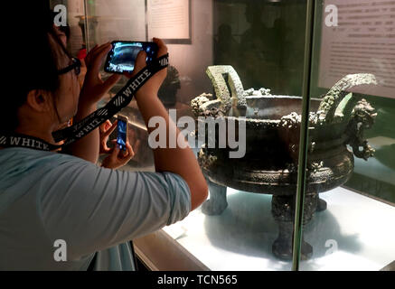 Zhengzhou, Chine, province de Henan. 9 juin, 2019. Un visiteur prend une photo d'une affiche au Musée du Henan bronzeware à Zhengzhou, capitale de la province du Henan en Chine centrale, le 9 juin 2019. Un crédit : Li/Xinhua/Alamy Live News Banque D'Images