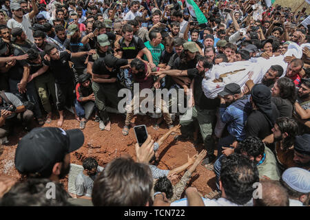 Annonce Dana, la Syrie. 09Th Juin, 2019. Les gens enterrer le corps de al-Abdel-Baset Sarout, un homme de 27 ans gardien syrien qui a rejoint la rébellion armée contre le président Bachar al-Assad, lors de ses funérailles après sa mort le samedi des blessures reçues lors de la bataille contre al-Assad·s forces dans la campagne de la province de Hama. L'ex-gardien de la Syrie·s de l'équipe junior a été parmi les premiers athlètes qui rejoint l'anti-al-Assad révolte quand il a éclaté en 2011. Credit : Anas Alkharboutli/dpa/Alamy Live News Banque D'Images