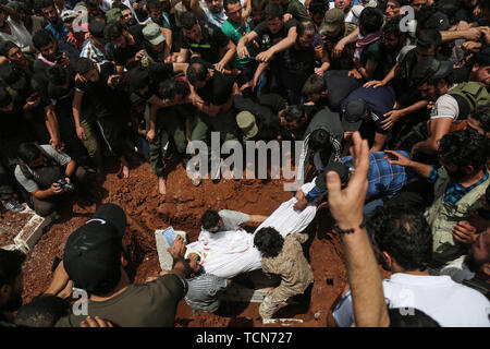 Annonce Dana, la Syrie. 09Th Juin, 2019. Les gens enterrer le corps de al-Abdel-Baset Sarout, un homme de 27 ans gardien syrien qui a rejoint la rébellion armée contre le président Bachar al-Assad, lors de ses funérailles après sa mort le samedi des blessures reçues lors de la bataille contre al-Assad·s forces dans la campagne de la province de Hama. L'ex-gardien de la Syrie·s de l'équipe junior a été parmi les premiers athlètes qui rejoint l'anti-al-Assad révolte quand il a éclaté en 2011. Credit : Anas Alkharboutli/dpa/Alamy Live News Banque D'Images