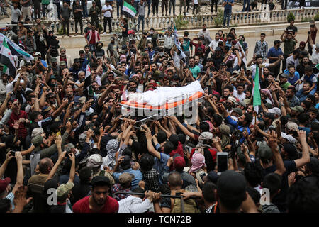 Annonce Dana, la Syrie. 09Th Juin, 2019. Les gens portent le corps de al-Abdel-Baset Sarout, un homme de 27 ans gardien syrien qui a rejoint la rébellion armée contre le président Bachar al-Assad, lors de ses funérailles après sa mort le samedi des blessures reçues lors de la bataille contre al-Assad·s forces dans la campagne de la province de Hama. L'ex-gardien de la Syrie·s de l'équipe junior a été parmi les premiers athlètes qui rejoint l'anti-al-Assad révolte quand il a éclaté en 2011. Credit : Anas Alkharboutli/dpa/Alamy Live News Banque D'Images