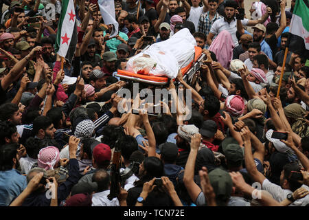 Annonce Dana, la Syrie. 09Th Juin, 2019. Les gens portent le corps de al-Abdel-Baset Sarout, un homme de 27 ans gardien syrien qui a rejoint la rébellion armée contre le président Bachar al-Assad, lors de ses funérailles après sa mort le samedi des blessures reçues lors de la bataille contre al-Assad·s forces dans la campagne de la province de Hama. L'ex-gardien de la Syrie·s de l'équipe junior a été parmi les premiers athlètes qui rejoint l'anti-al-Assad révolte quand il a éclaté en 2011. Credit : Anas Alkharboutli/dpa/Alamy Live News Banque D'Images