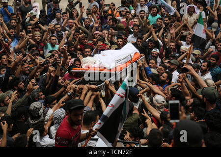 Annonce Dana, la Syrie. 09Th Juin, 2019. Les gens portent le corps de al-Abdel-Baset Sarout, un homme de 27 ans gardien syrien qui a rejoint la rébellion armée contre le président Bachar al-Assad, lors de ses funérailles après sa mort le samedi des blessures reçues lors de la bataille contre al-Assad·s forces dans la campagne de la province de Hama. L'ex-gardien de la Syrie·s de l'équipe junior a été parmi les premiers athlètes qui rejoint l'anti-al-Assad révolte quand il a éclaté en 2011. Credit : Anas Alkharboutli/dpa/Alamy Live News Banque D'Images