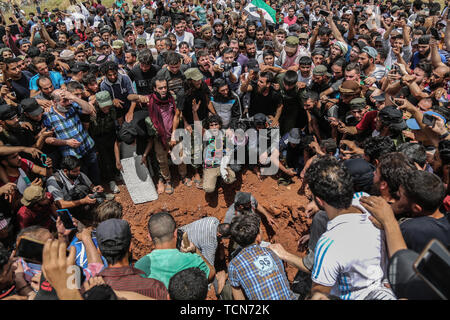 Annonce Dana, la Syrie. 09Th Juin, 2019. Les gens enterrer le corps de al-Abdel-Baset Sarout, un homme de 27 ans gardien syrien qui a rejoint la rébellion armée contre le président Bachar al-Assad, lors de ses funérailles après sa mort le samedi des blessures reçues lors de la bataille contre al-Assad·s forces dans la campagne de la province de Hama. L'ex-gardien de la Syrie·s de l'équipe junior a été parmi les premiers athlètes qui rejoint l'anti-al-Assad révolte quand il a éclaté en 2011. Credit : Anas Alkharboutli/dpa/Alamy Live News Banque D'Images