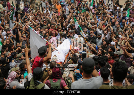 Annonce Dana, la Syrie. 09Th Juin, 2019. Les gens portent le corps de al-Abdel-Baset Sarout, un homme de 27 ans gardien syrien qui a rejoint la rébellion armée contre le président Bachar al-Assad, lors de ses funérailles après sa mort le samedi des blessures reçues lors de la bataille contre al-Assad·s forces dans la campagne de la province de Hama. L'ex-gardien de la Syrie·s de l'équipe junior a été parmi les premiers athlètes qui rejoint l'anti-al-Assad révolte quand il a éclaté en 2011. Credit : Anas Alkharboutli/dpa/Alamy Live News Banque D'Images