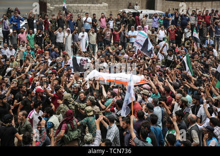 Annonce Dana, la Syrie. 09Th Juin, 2019. Les gens portent le corps de al-Abdel-Baset Sarout, un homme de 27 ans gardien syrien qui a rejoint la rébellion armée contre le président Bachar al-Assad, lors de ses funérailles après sa mort le samedi des blessures reçues lors de la bataille contre al-Assad·s forces dans la campagne de la province de Hama. L'ex-gardien de la Syrie·s de l'équipe junior a été parmi les premiers athlètes qui rejoint l'anti-al-Assad révolte quand il a éclaté en 2011. Credit : Anas Alkharboutli/dpa/Alamy Live News Banque D'Images