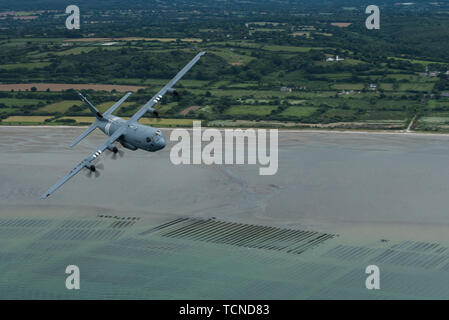 Un U.S. Air Force C-130J Super Hercules, affecté à la 37e Escadron de transport aérien, la base aérienne de Ramstein, Allemagne, porte les marques de whisky "7", parce qu'elle vole au-dessus de l'Utah Beach, Normandie, France, 6 juin 2019. La 37e lignée comme' s'inspire de la 37e Escadron de transport de troupes, qui portait la "Whiskey", 7 ou W7 sur leurs aéronefs lorsqu'ils ont effectué plus de gouttes paratrooper Normandie, France au cours de l'Opération Neptune, le 6 juin 1944. (U.S. Photo de l'Armée de l'air par la Haute Airman Devin M. Rumbaugh) Banque D'Images