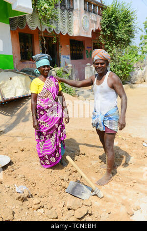 Un Tamoul man loading un lourd panier de sable d'une femme à la tête. Banque D'Images