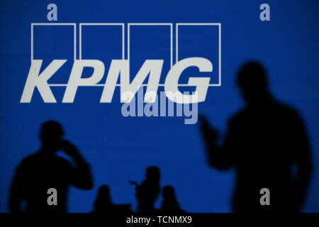 Le logo de KPMG est vu sur un écran LED à l'arrière-plan tandis qu'une personne utilise la silhouette d'un smartphone dans l'avant-plan (usage éditorial uniquement) Banque D'Images