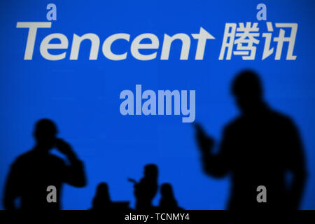 Le logo de Tencent est vu sur un écran LED à l'arrière-plan tandis qu'une personne utilise la silhouette d'un smartphone dans l'avant-plan (usage éditorial uniquement) Banque D'Images