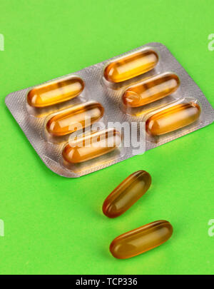 Capsules emballées en ampoule sur fond vert Banque D'Images