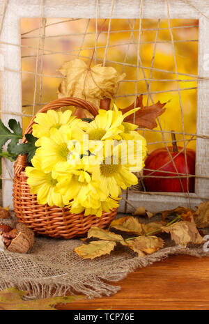 Composition d'automne avec des fleurs dans un panier et de feuilles sur fond lumineux Banque D'Images