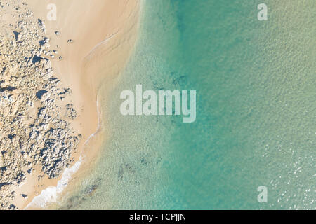 Haut de la magnifique vue sur une plage au lever du soleil avec de belles lignes courbes, l'eau turquoise peu profonde dans une destination de vacances tropicales Banque D'Images