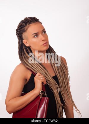 Portrait d'une fille européenne avec des tresses africaines, rasé des temples et un sac rouge foncé sur un fond blanc Banque D'Images