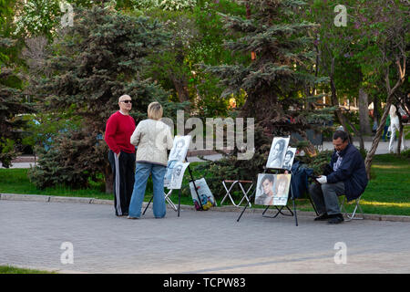 Novosibirsk, Russie - 05.28.2019 : Artistes avec des photos de gens à chevalets dans le parc de la ville offrent de tirer un portrait au passant par une chaude journée claire Banque D'Images