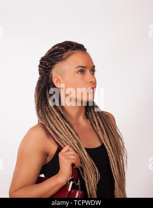 Portrait d'une fille européenne avec des tresses africaines, rasé des temples et un sac rouge foncé sur un fond blanc Banque D'Images