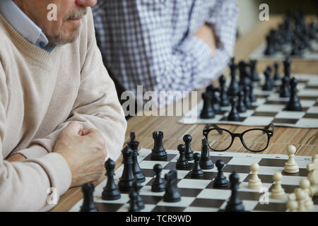 Deux joueurs d'échecs graves assis dans la rangée avec les mains croisées au cours difficile tournoi d'échecs Banque D'Images