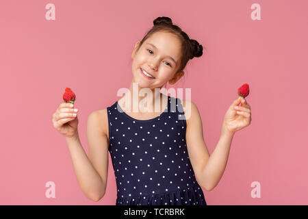 Adorable petite fille tenant deux fraises rouges frais Banque D'Images