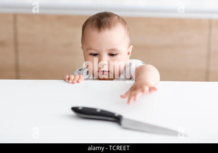 Situation dangereuse dans la cuisine. Enfant essaie d'obtenir un couteau de cuisine, Banque D'Images