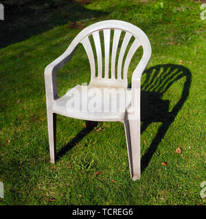 Un fauteuil de jardin en plastique placé sur l'herbe, extérieur shot Banque D'Images