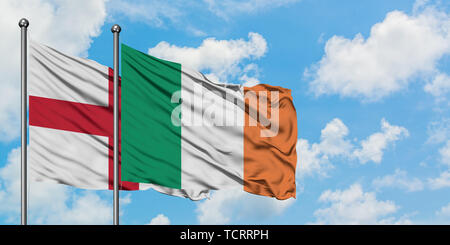 L'Angleterre et l'Irlande drapeaux dans le vent contre ciel bleu nuageux blanc ensemble. Concept de diplomatie, de relations internationales. Banque D'Images