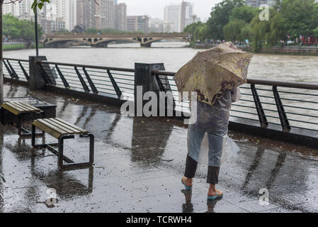 Chengdu, Sichuan Province, China - Juillet 11,2018 : Homme avec un parapluie regardant Jinjiang river pour les inondations après de fortes pluies dans la province du Sichuan. Banque D'Images