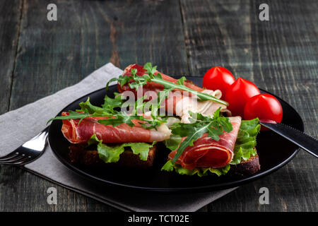 Sur la table il y a un plat avec des sandwichs jamon, tomate et verts Banque D'Images