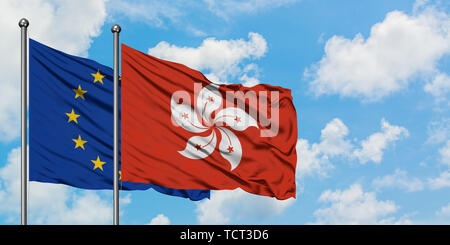 L'Union européenne et Hong Kong drapeaux dans le vent contre ciel bleu nuageux blanc ensemble. Concept de diplomatie, de relations internationales. Banque D'Images