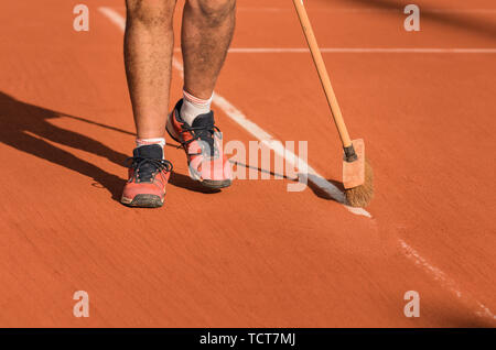 Homme nettoie, nettoyage de la ligne de tennis sur terre battue avec un balai Banque D'Images