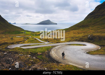 Jeune patineur avec son skateboard regarde le paysage magnifique des îles Féroé Banque D'Images