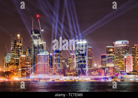 Front de mer de la ville de Sydney CBD hautes tours lumineuses reflétant les éclairages dans les eaux trouble de Harbour pendant des Sydney avec laser bleu Banque D'Images