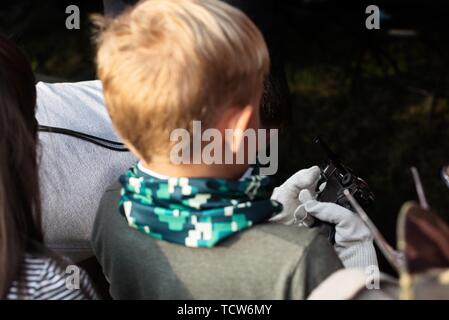 Un garçon avec des armes à feu. Little Boy holding véritable arme dans la main. Happy boy avec pistolet pistolet à jouer à l'extérieur. Banque D'Images