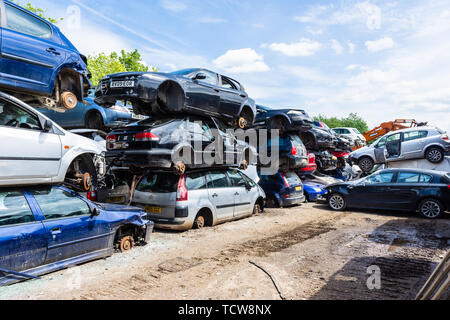 Les voitures avec leurs roues enlevés sont empilées dans des piles de 3 voitures avec des chemins entre les disjoncteurs dans un parc à ferrailles Banque D'Images