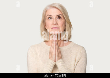 Sincères de femme en prière isolé sur fond gris studio Banque D'Images