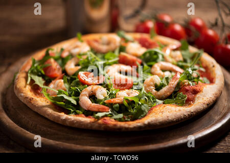 Pizza couverte de roquette et crevettes sur table en bois close up Banque D'Images